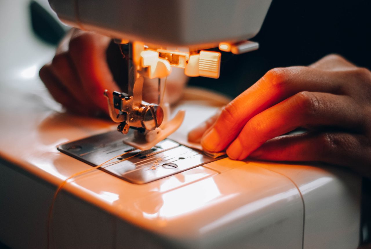 Detailed view of hands using a sewing machine, perfect for crafting or tailoring concepts.