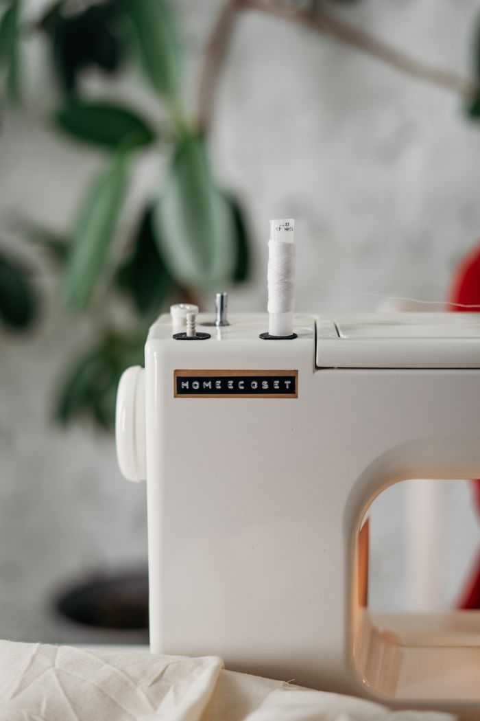Detailed close-up of a sewing machine with a spool, set in a cozy indoor space.